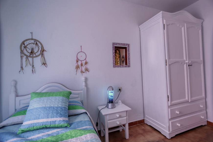 Dormitorio con cama individual, armario blanco y mesita de noche