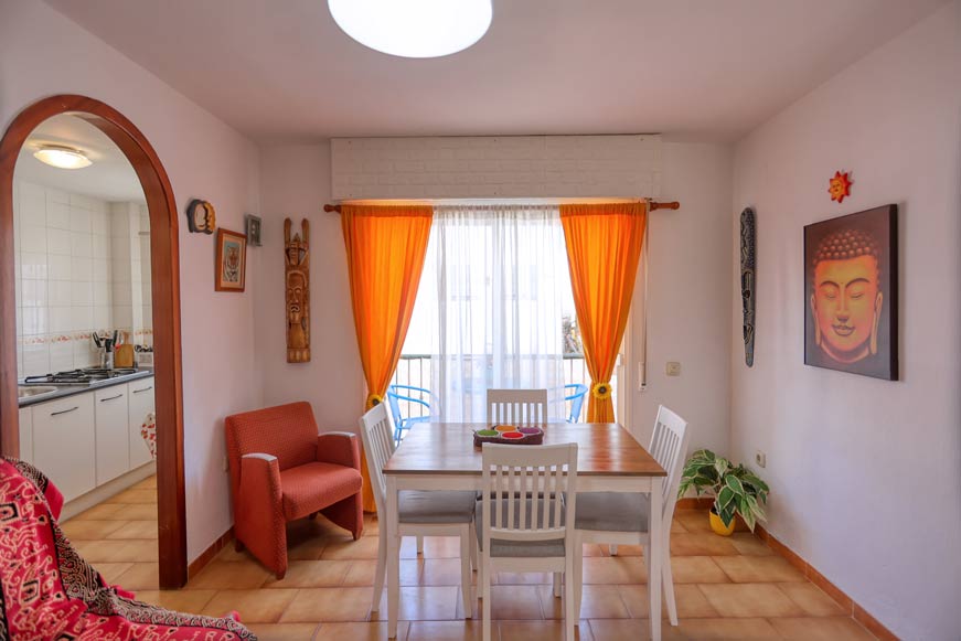 Comedor con mesa de madera y cortinas naranjas desde la esquina