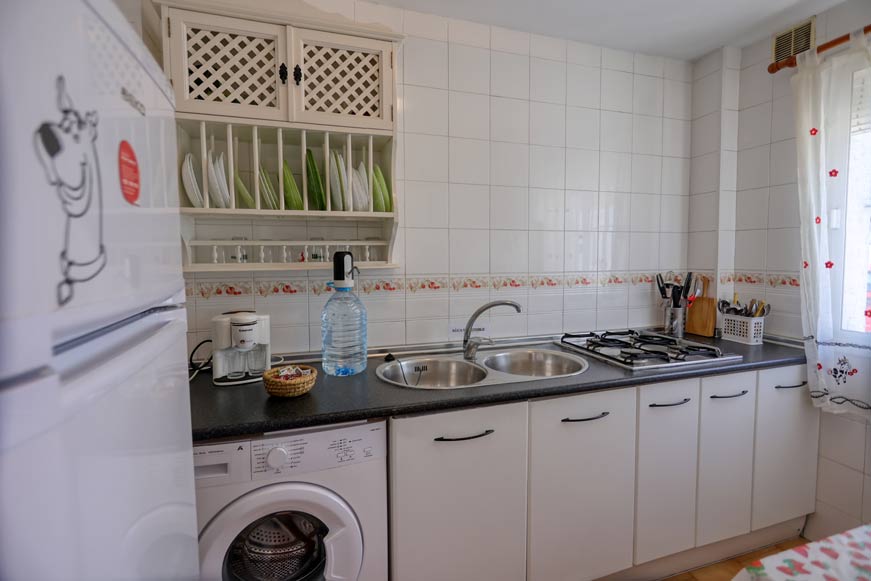 Vista de cocina luminosa con fregadero doble y alacena blanca