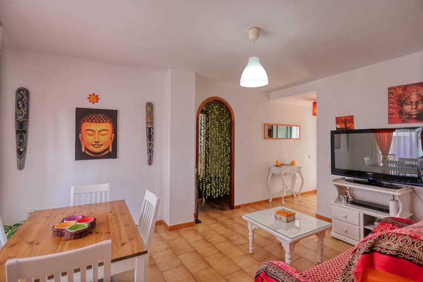 Vista desde la cocina del salón con televisión, mesa de centro y decoración colorida en pared