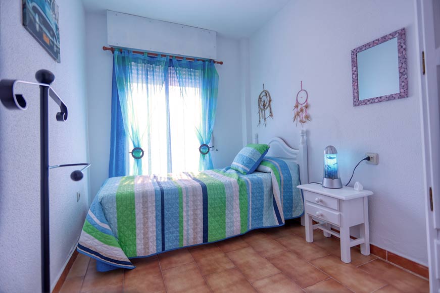 Dormitorio con cama individual y ropa de cama colorida