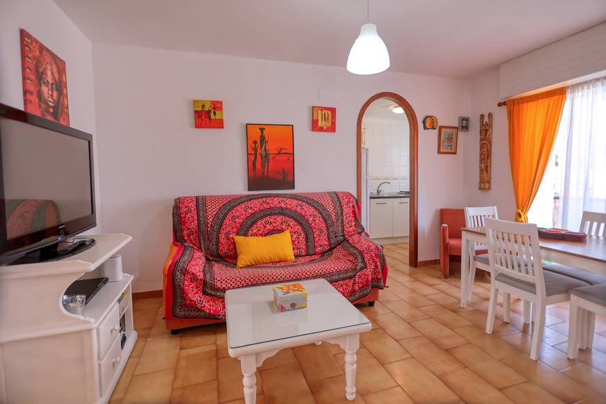 salón con sofá, mesa de centro y zona de comedor en apartamento en Los Caños de Meca en alquiler