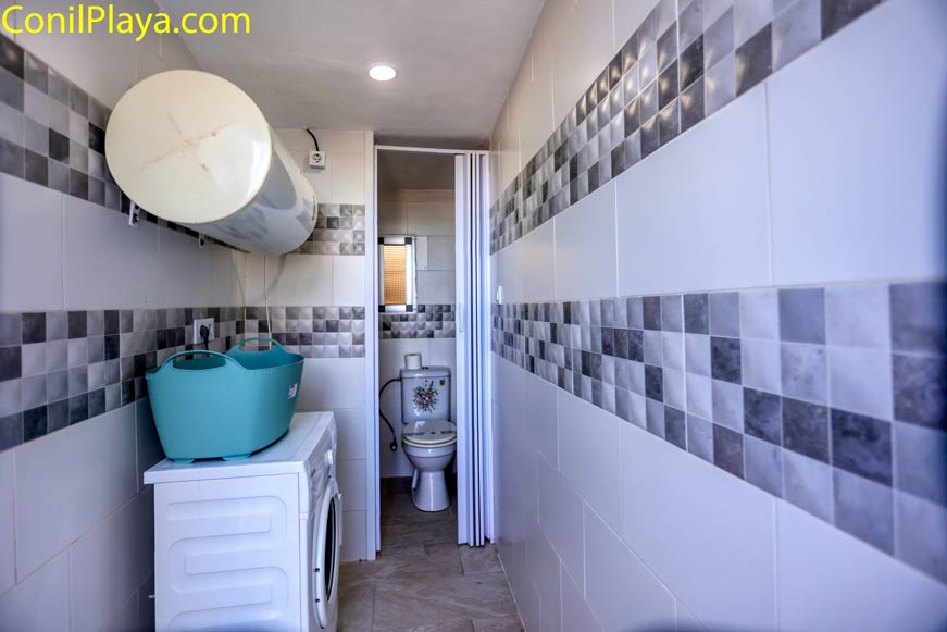 Cuarto de baño pequeño con lavadora, termo y aseo al fondo