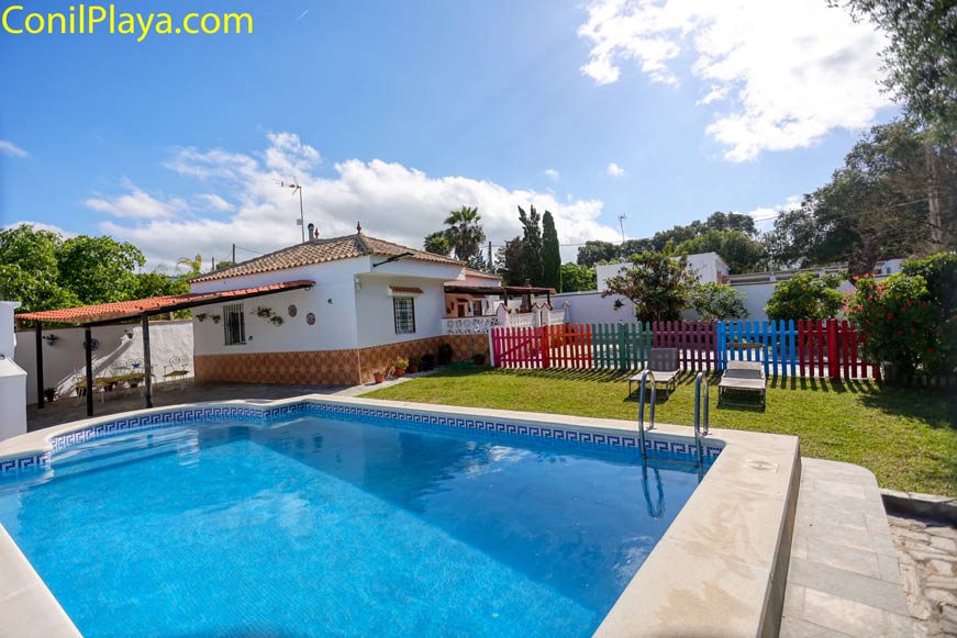 Piscina privada con escalones y zona amplia de césped con 2 tumbonas en recinto vallado