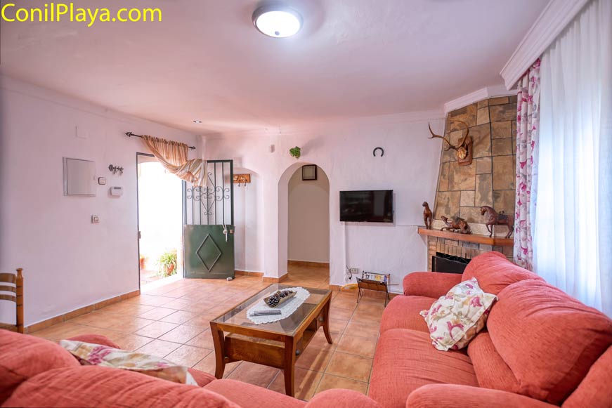 Salón con sofás naranjas, chimenea de piedra y mesa de centro de madera