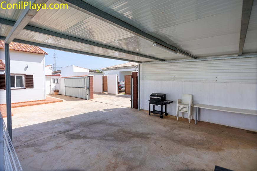 Aparcamiento techado con barbacoa y sillas y mesa para celebraciones