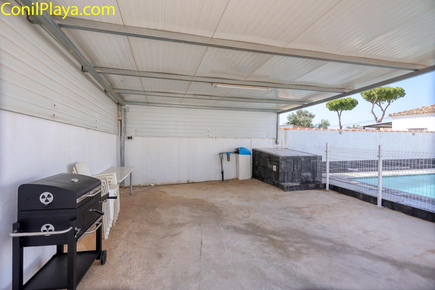 Aparcamiento techado con barbacoa y junto a la piscina en una vivienda