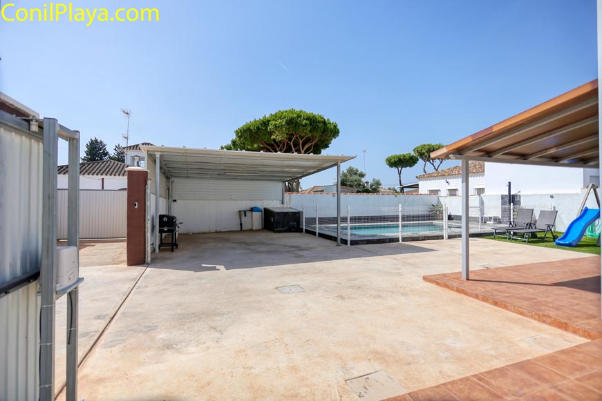 Aparcamiento techado junto a piscina y mobiliario exterior en vivienda