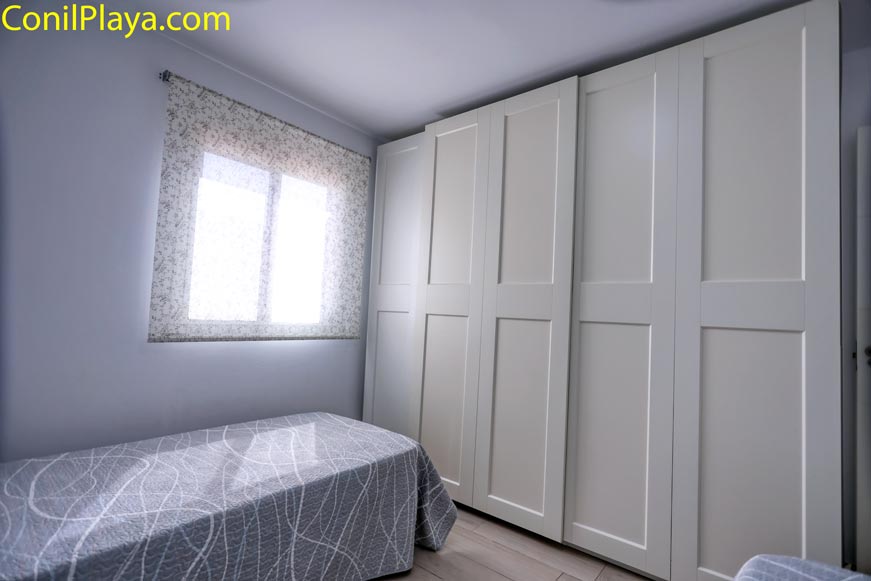 Dormitorio con cama individual y gran armario blanco empotrado
