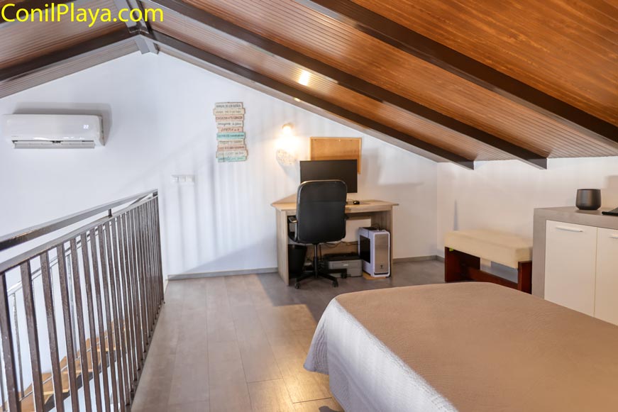 Dormitorio abuhardillado con cama escritorio y zona de estudio visible
