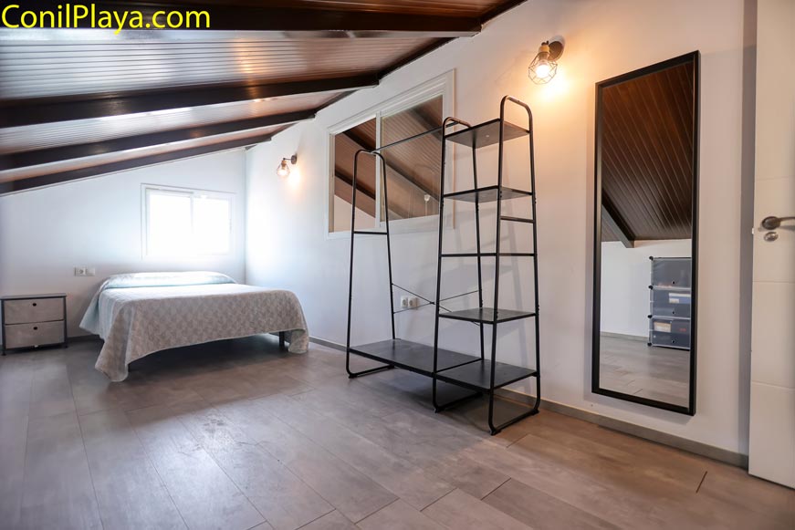 Dormitorio amplio abuhardillado con cama doble y armario metálico abierto