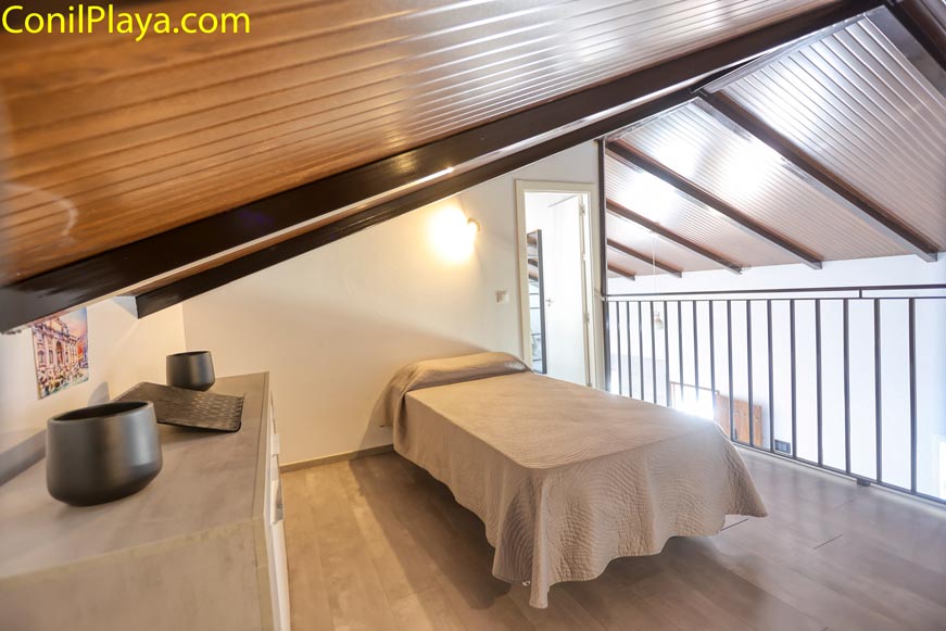 Dormitorio con cama individual bajo techo de madera en planta superior