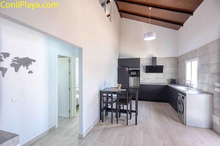 Cocina moderna con electrodomésticos y mesa desde el pasillo