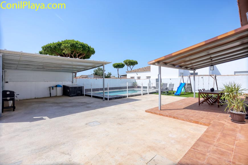 Patio con piscina vallada, aparcamiento amplio techado y porche con mesa y sillas