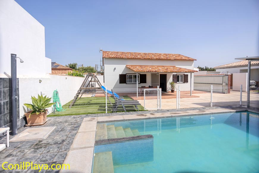 Vista frontal de la casa con piscina privada vallada y jardín