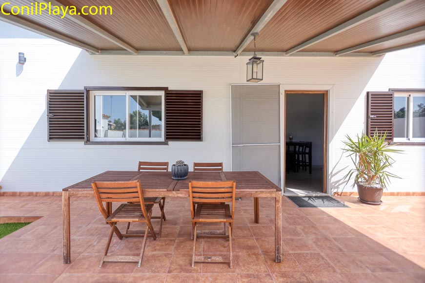 Porche exterior con mesa y sillas de madera delante de vivienda