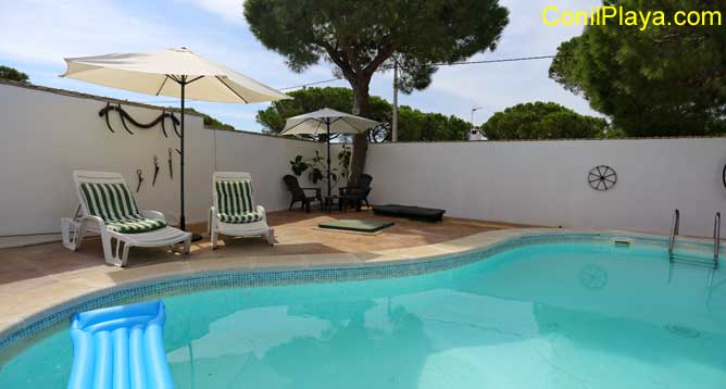 Piscina de riñón con sombrilla y tumbonas