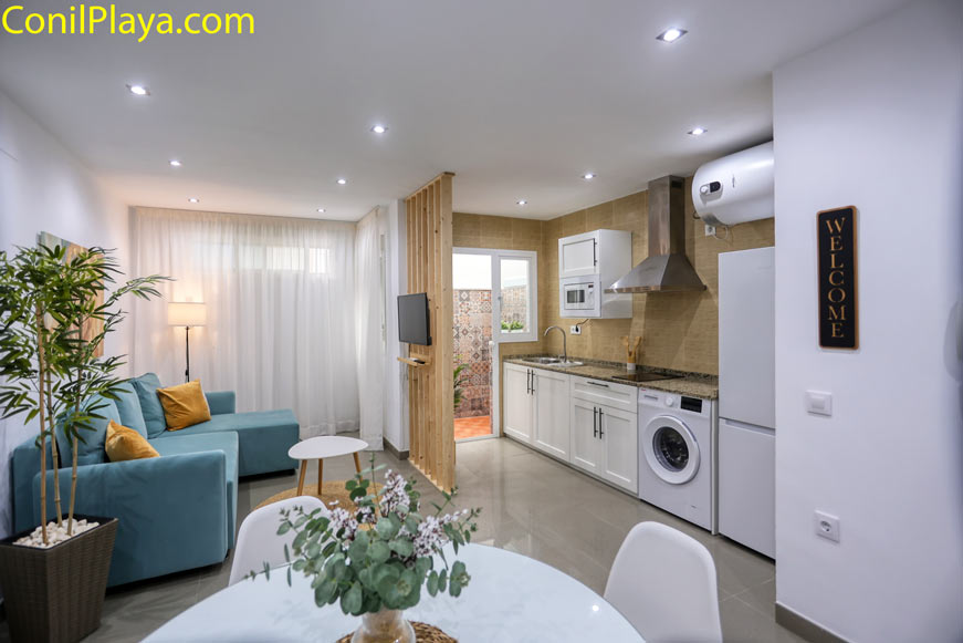 Salón luminoso con sofá azul cocina abierta y detalles modernos