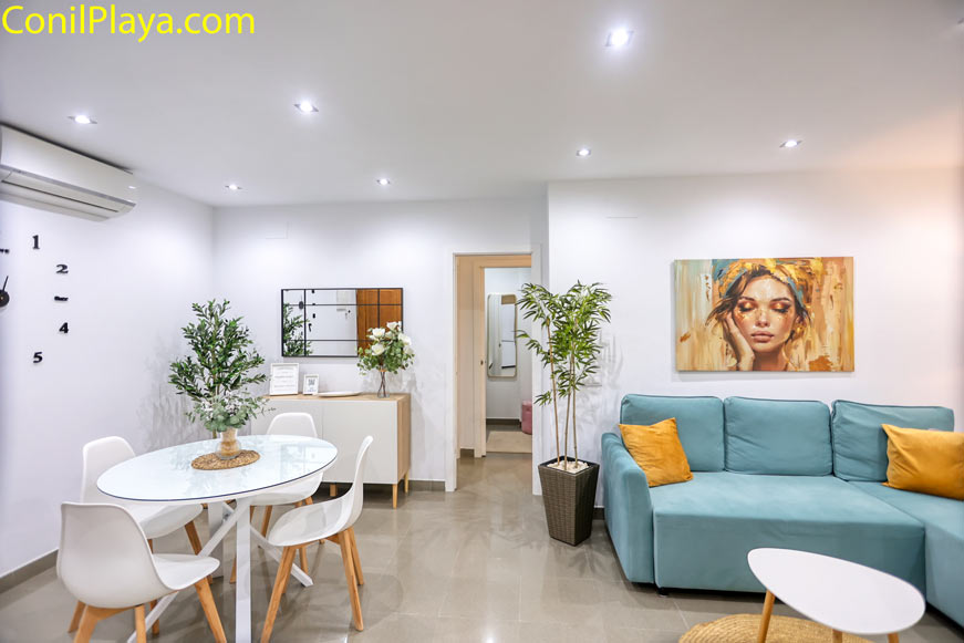 Comedor con mesa redonda, sofá azul y decoración minimalista en apartamento en Conil