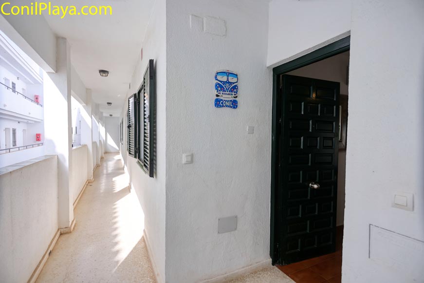 Entrada exterior de vivienda con puerta abierta desde el pasillo del edificio
