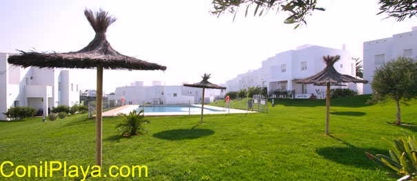 La piscina está rodeada de amplios jardínes con césped y sombrillas.