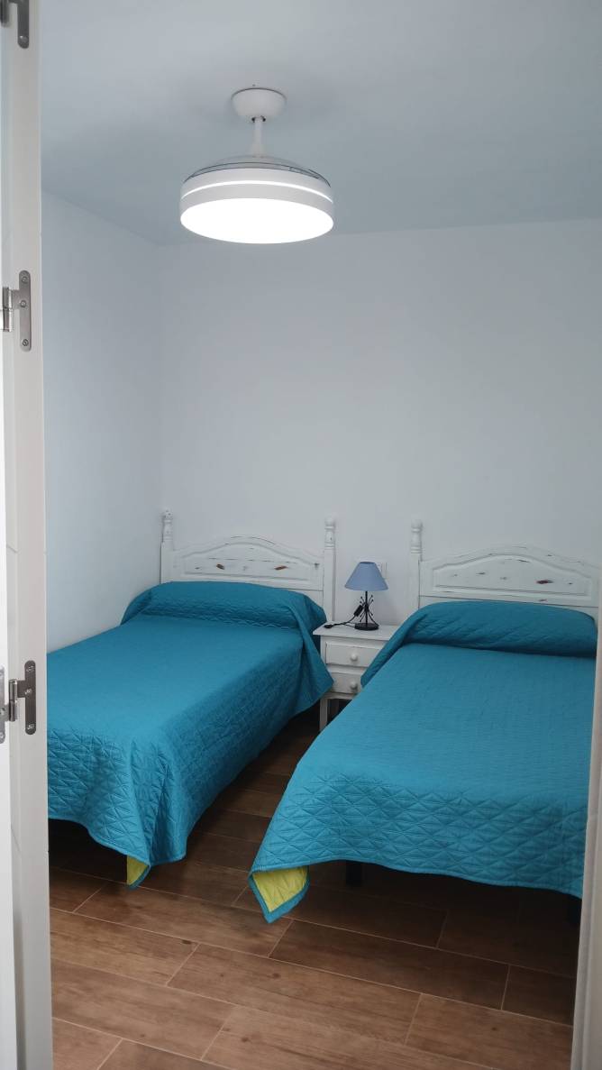 Dormitorio con 2 camas y lampara con ventilador de techo