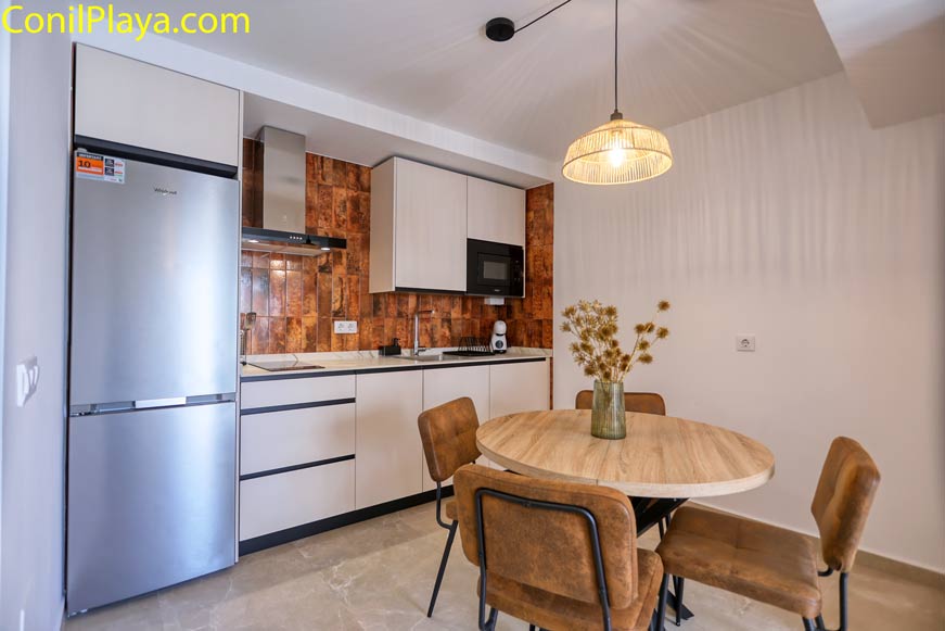 Cocina con mesa redonda y sillas junto a electrodomésticos nuevos