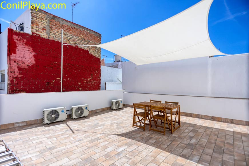 Terraza amplia con mesa y sillas bajo toldo vista desde la entrada