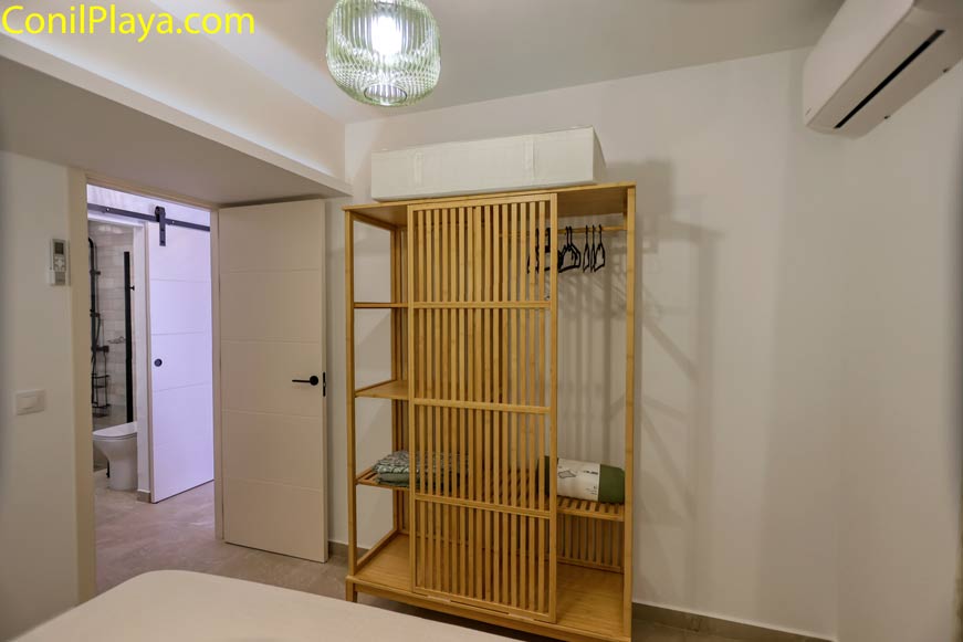 Vista desde el dormitorio principal con armario de madera abierto y baño anexo