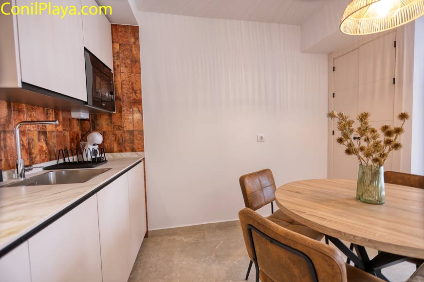 Cocina moderna con mesa redonda y sillas junto a la entrada