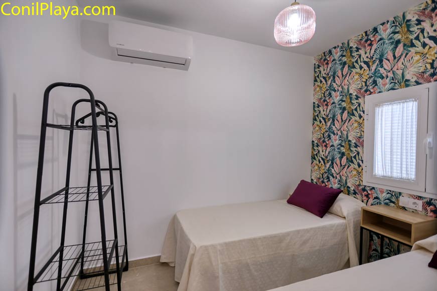 Dormitorio con estructura de armario, dos camas individuales y pared decorada con papel floral