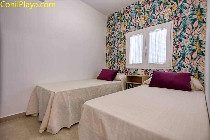 Dormitorio con dos camas individuales y pared decorada con papel pintado floral