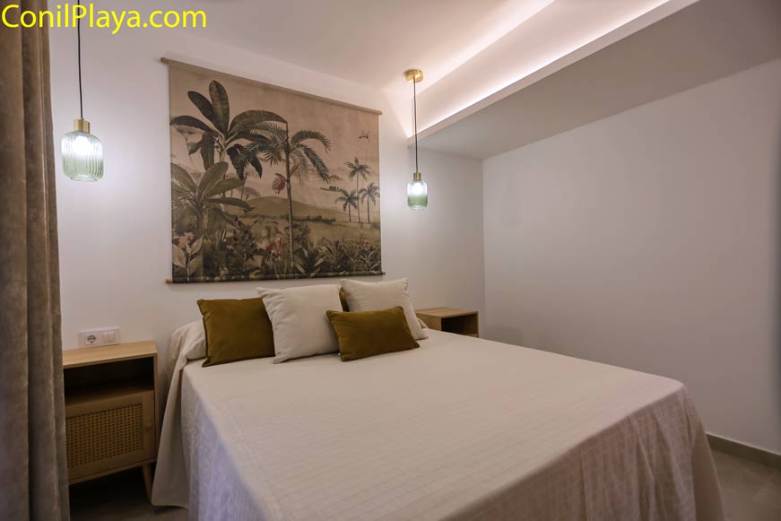 Dormitorio con cama doble, cabecero decorativo y lámparas colgantes modernas
