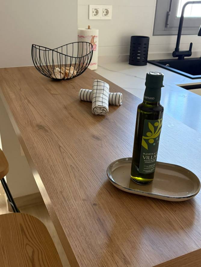 Detalle de encimera de madera con botella de aceite de oliva y cuenco de conchas