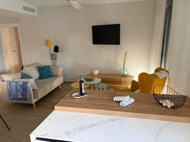 Perspectiva desde la cocina hacia el salón con mueble de TV de madera natural