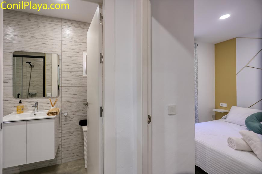 Cuarto de baño moderno junto al dormitorio con toallas y espejo grande