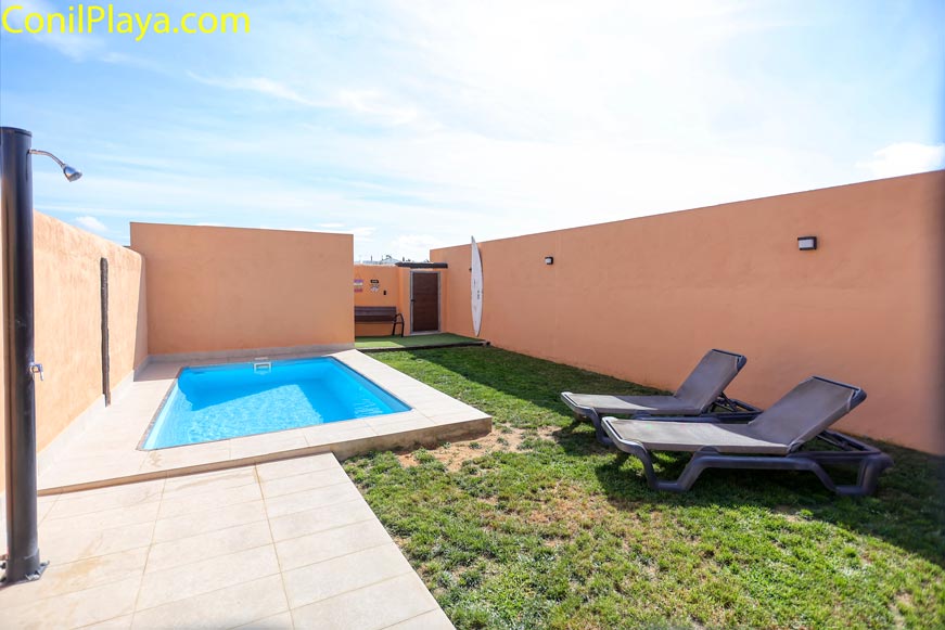 Pequeña piscina privada con césped natural y tumbonas vista desde la entrada exterior