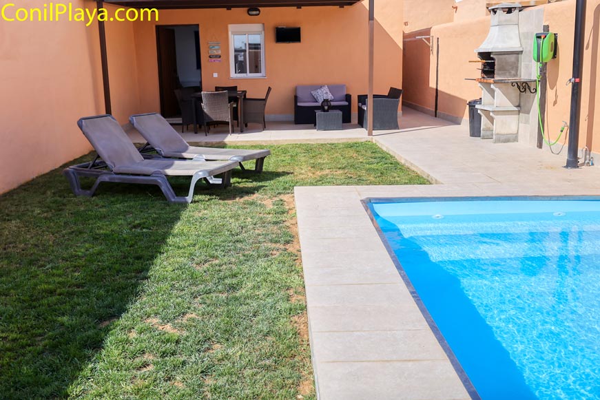Jardín con piscina, tumbonas y barbacoa junto a una casa