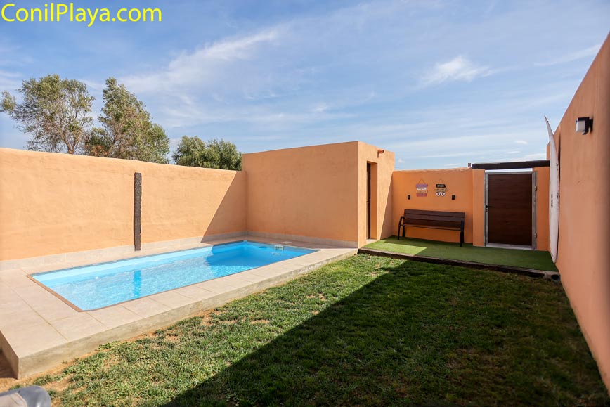 Zona exterior privada con pequeña piscina junto a césped y paredes color salmón