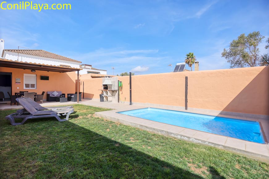 Zona exterior con piscina privada, césped con tumbonas y barbacoa