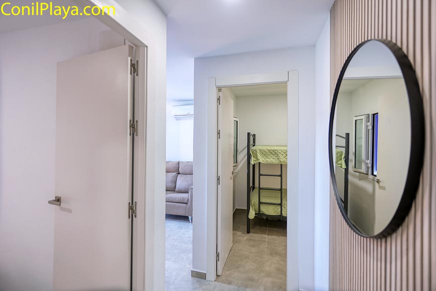 Pasillo con acceso a dormitorio con litera y salón con sofá al fondo