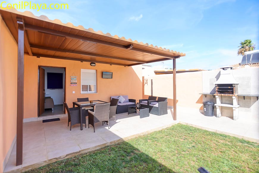 Porche exterior con muebles de jardín y barbacoa junto a césped