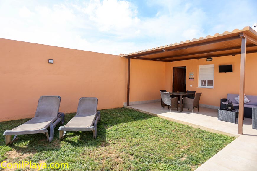 Jardín privado con césped natural, tumbonas y porche amueblado junto a la casa