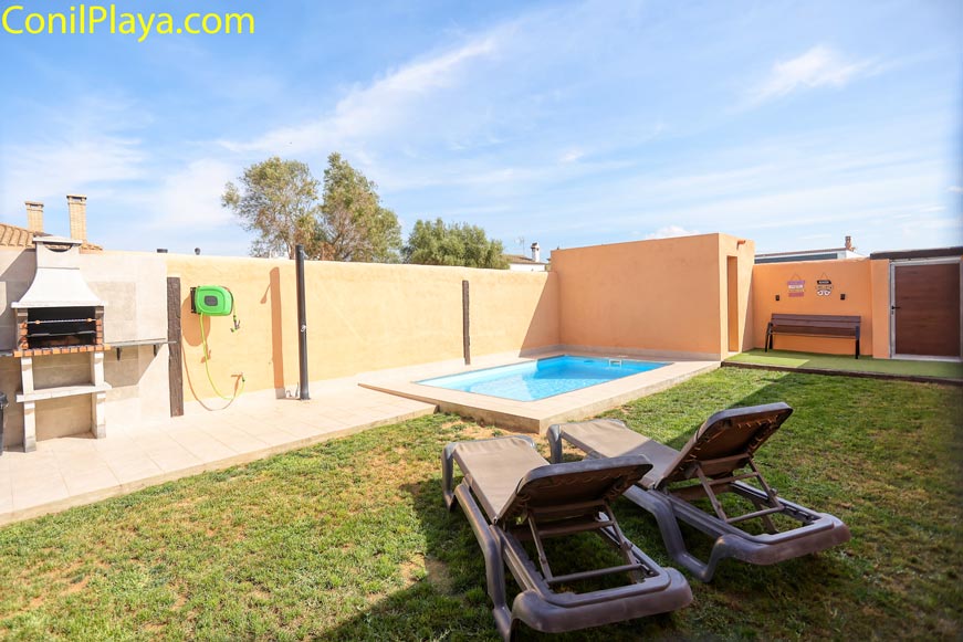 Zona de piscina privada con barbacoa y tumbonas en alojamiento en alquiler