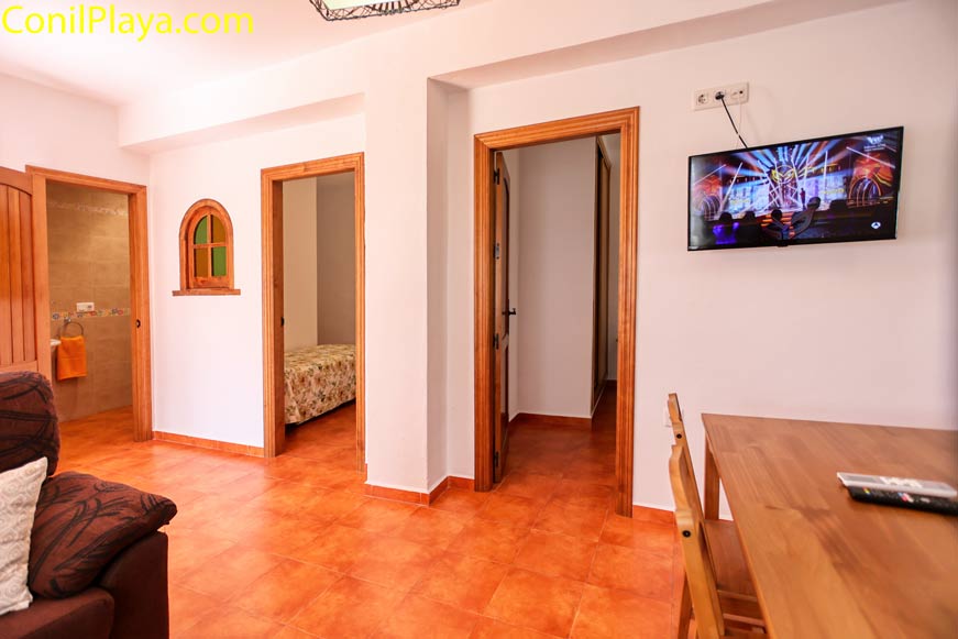 Salón con suelo cerámico, televisor y acceso a dormitorio y baño