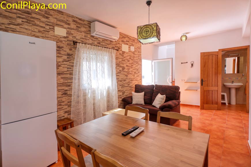 Salón con sofá marrón, mesa de comedor y aire acondicionado
