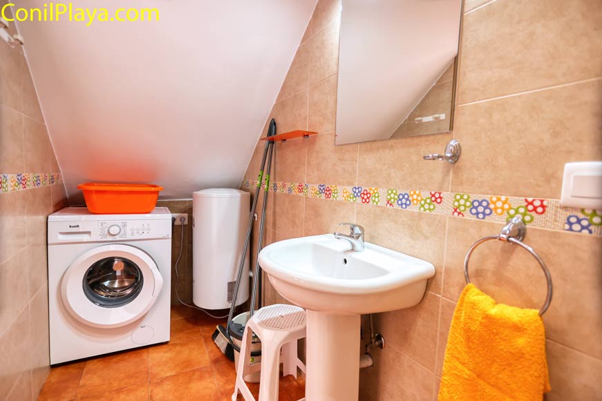 Cuarto de baño con lavadora, termo eléctrico y lavabo bajo techo inclinado