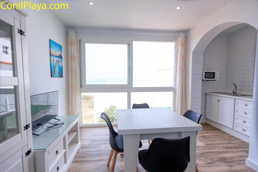 Comedor con mesa y sillas junto a ventana grande y cocina integrada