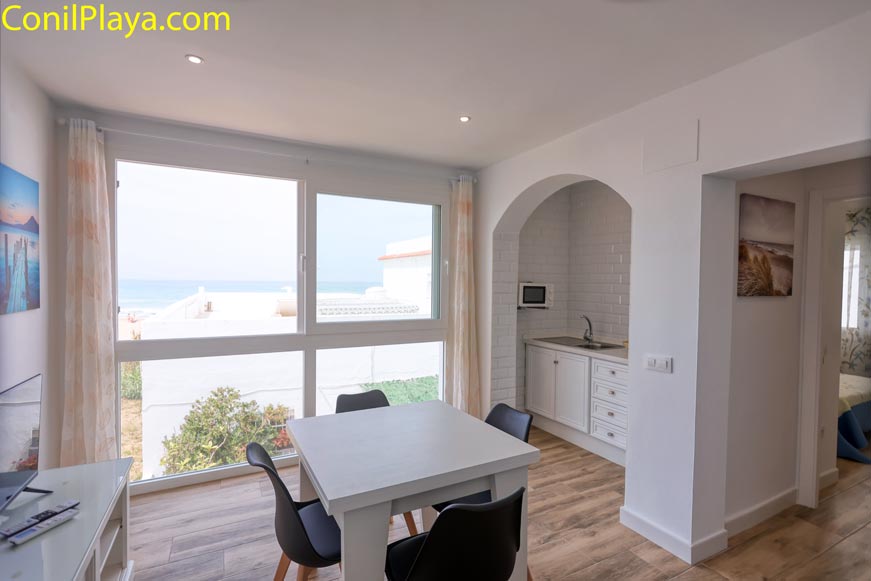 Comedor con mesa blanca, ventanas grandes y acceso a cocina