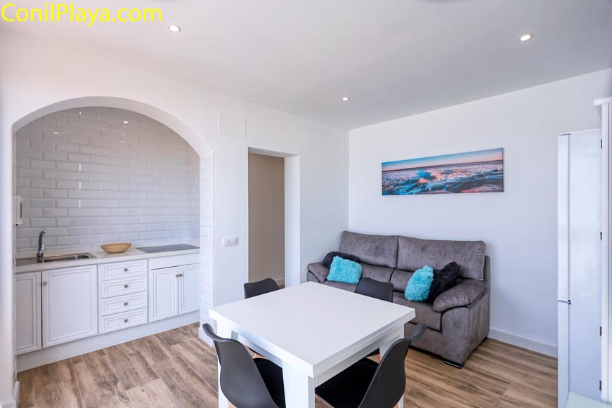 Salón con sofá gris y mesa de comedor junto a cocina integrada